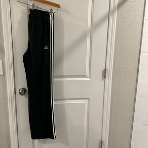 Adidas black and white track pants with zips at bottom.